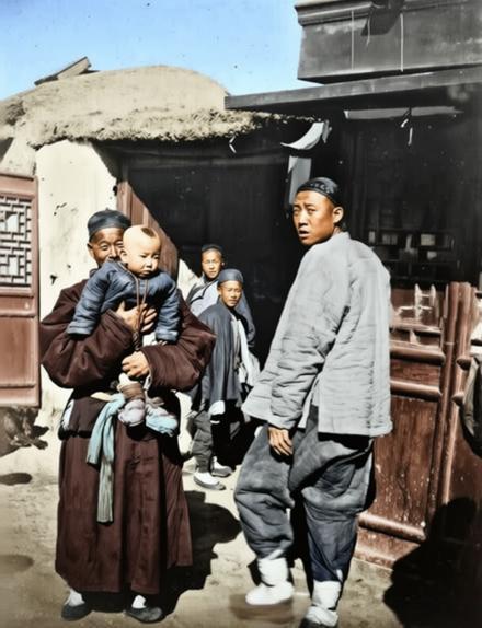 清末民初，北方城市街头，左侧一位年长的男子，怀中稳稳抱着一个穿着厚实棉袄的幼童，