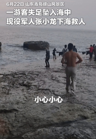 山东青岛崂山风景区，一名游客不慎掉进海里，岸上的同伴和路人都急得团团转。当时风浪