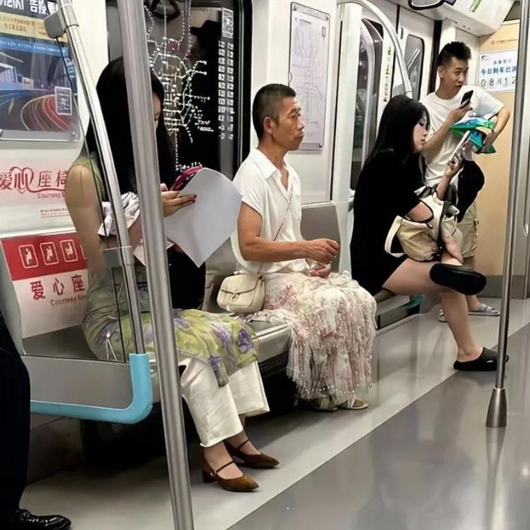 地铁上这一幕，真把我看愣了车厢里，一位大爷穿着碎花长裙，淡定地坐在座位上。