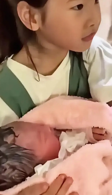 辛苦，女儿为了陪妈妈生产，一夜没睡，等妈妈产下弟弟以后，抱着弟弟静静的等着妈妈从