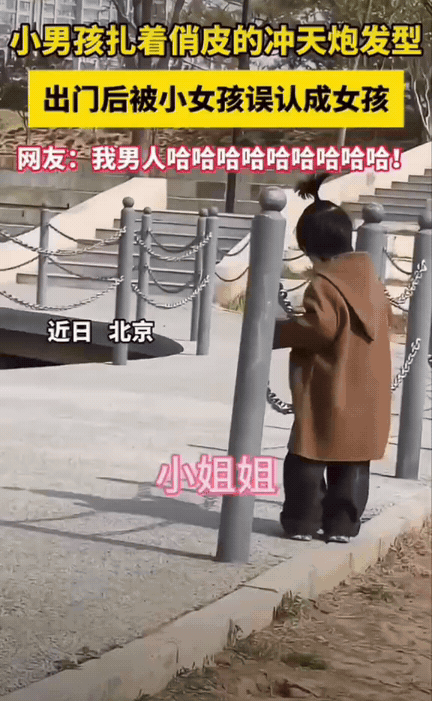笑不活了！北京公园，一个小男孩扎着可爱的朝天辫，正在公园里玩耍。旁边的小妹妹看着