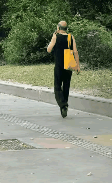 一个秃顶爷们，一边走路，一边抽着烟。看看着装打扮，就是一爷们，