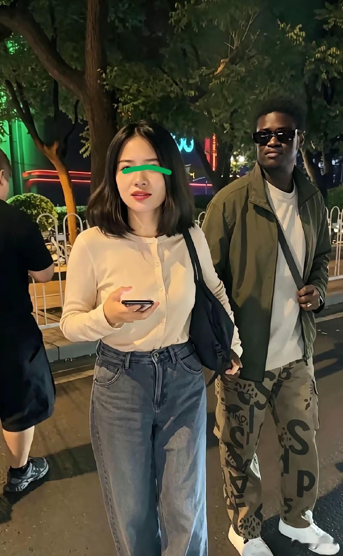 一中国姑娘找了一个黑人小伙，女子牵着小伙的手，怎么感觉这位小伙好像不开心，女子反