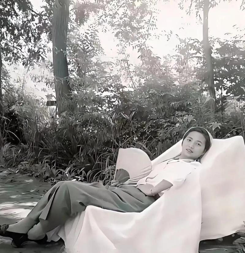 这是1956年，陈毅夫人张茜手拿扇子，斜躺在树下椅子上休憩的老照片。张茜那张照