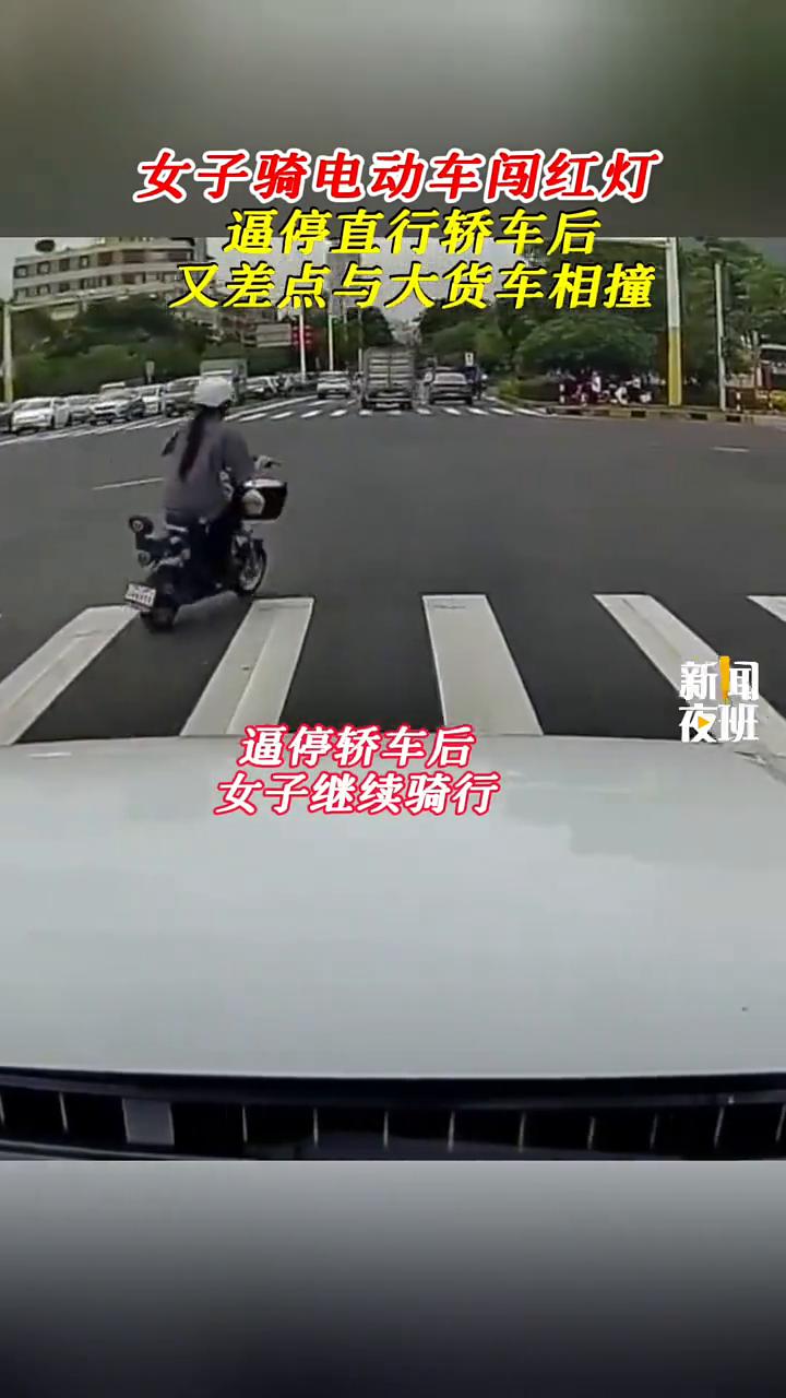 女子骑电动车闯红灯，逼停直行轿车后又差点与大货车相撞。夜班新闻。女子骑电动车