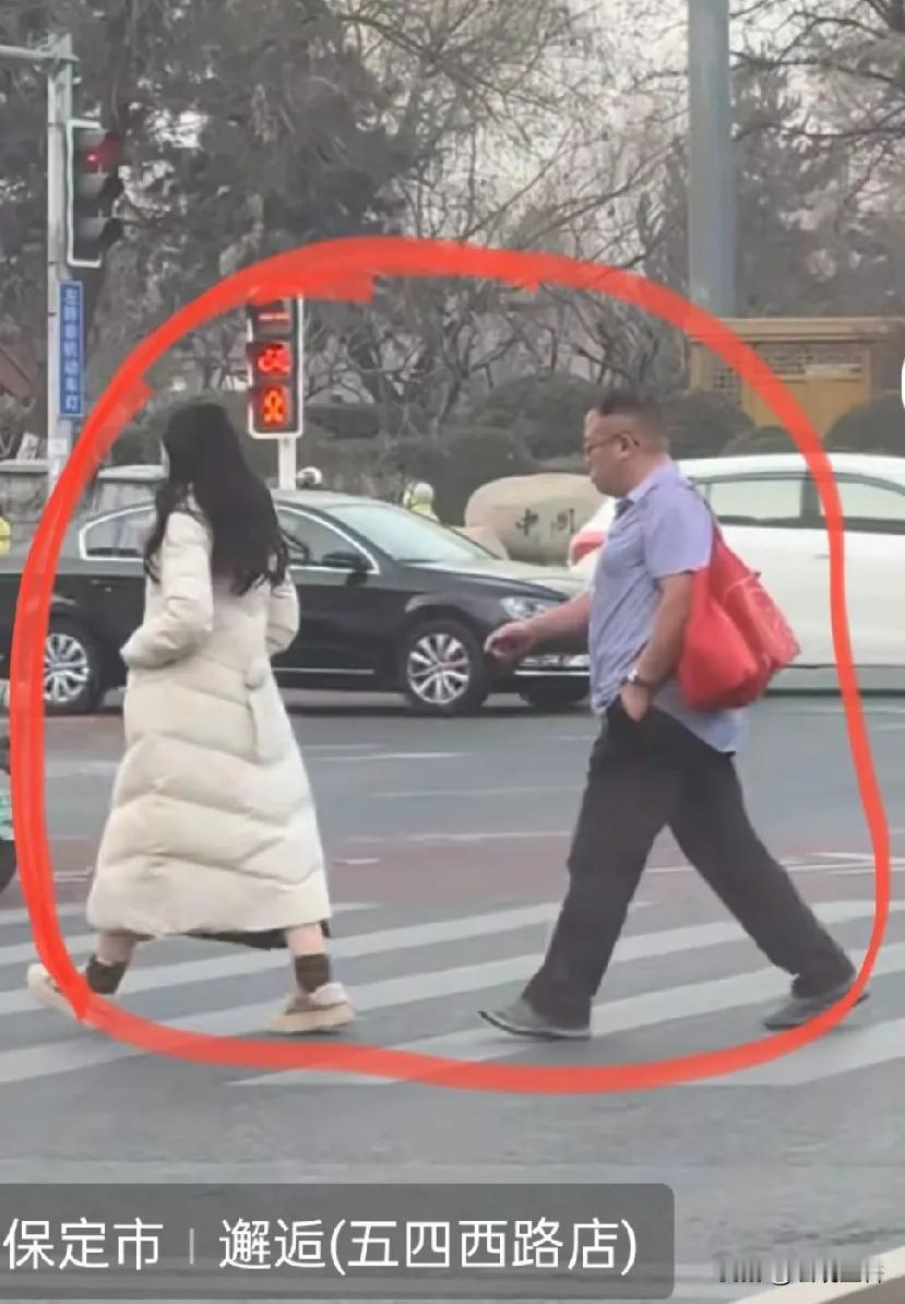 他是血压偏高吗？近日，河北保定街头出现奇异的一幕:一个穿长款羽绒服的女子和一个