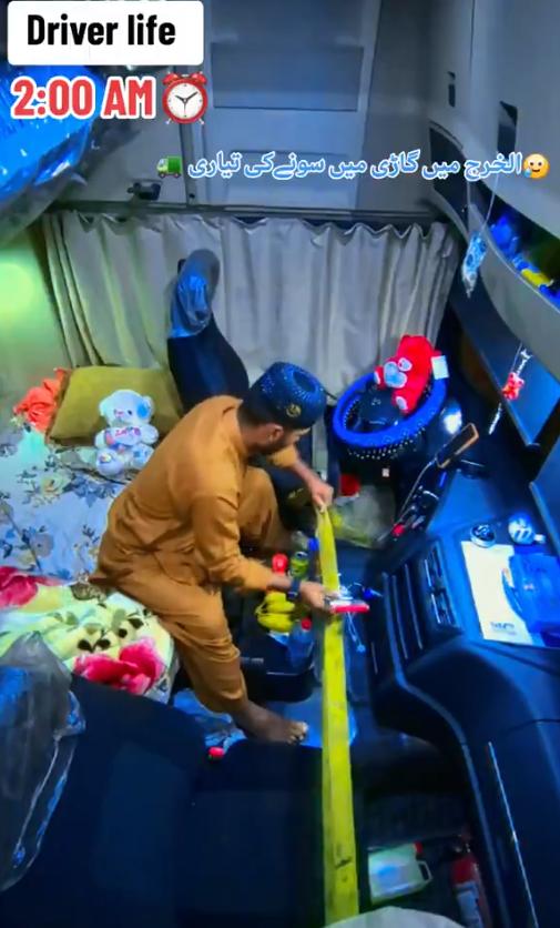 巴基斯坦一名卡车司机在休息区睡觉前，用安全带将卡车两边车门拉好绑住，以防止小偷进