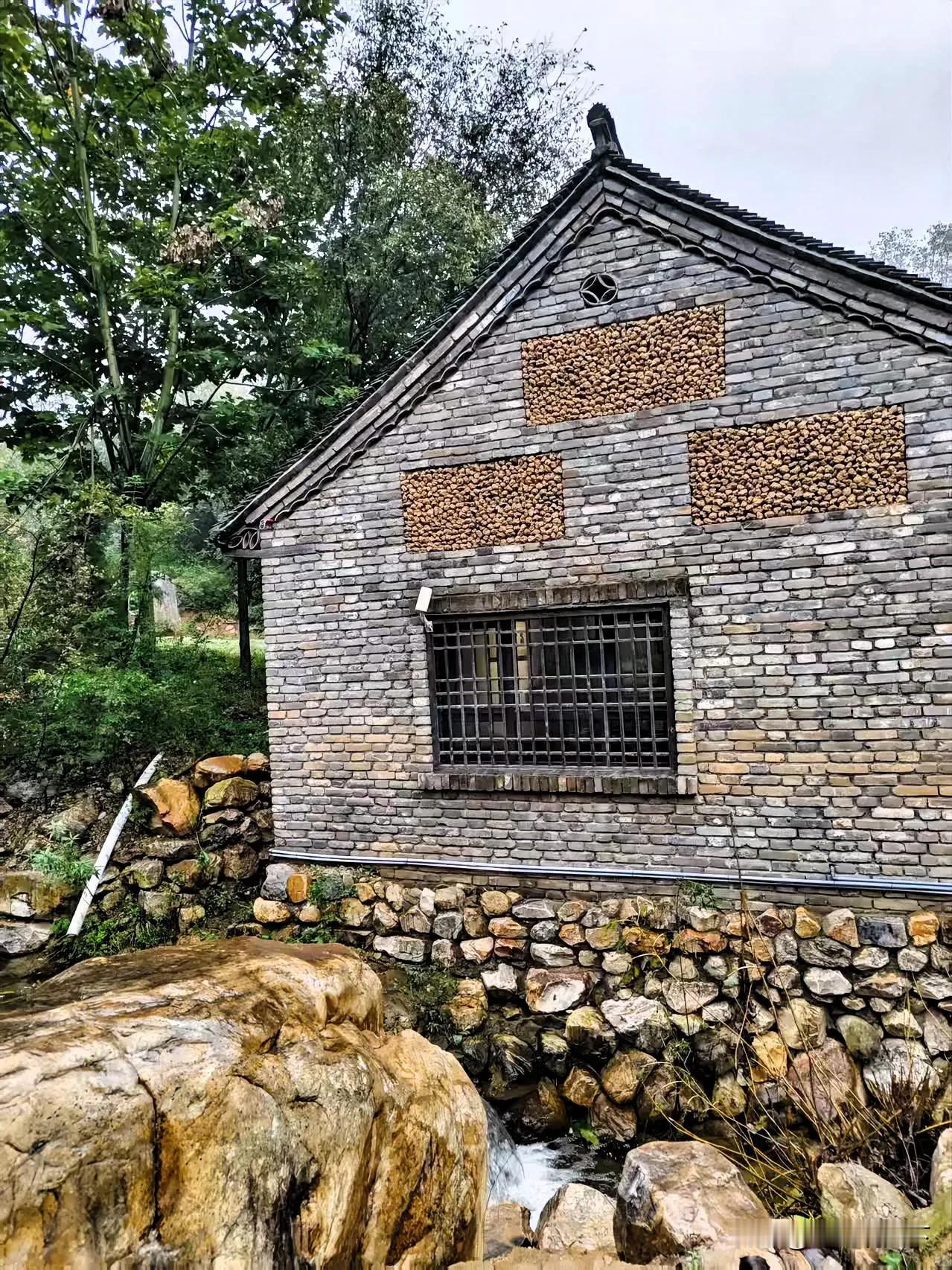 在烟雨朦胧的山林间，一座青砖古厝静静伫立。灰砖垒就的墙面上，几块嵌入的“坚果墙”