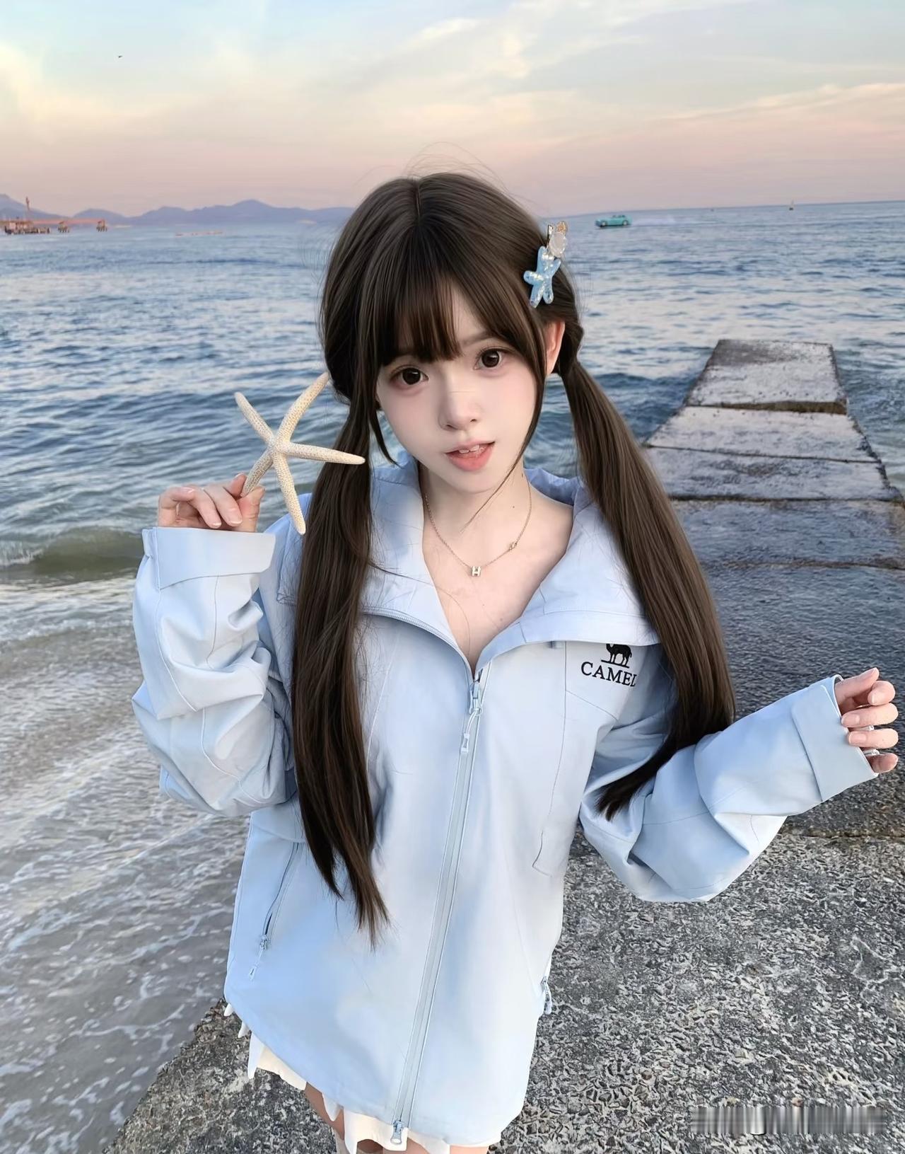 海边的小可爱拿着海星拍照。