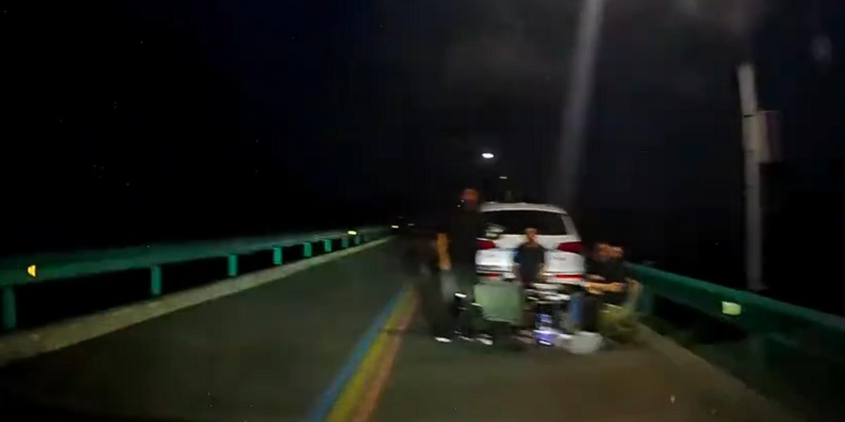 司机避开远光灯惊见多人车道聚餐对向车道远光灯晃人眼，同向车道四个人坐着吃席。这