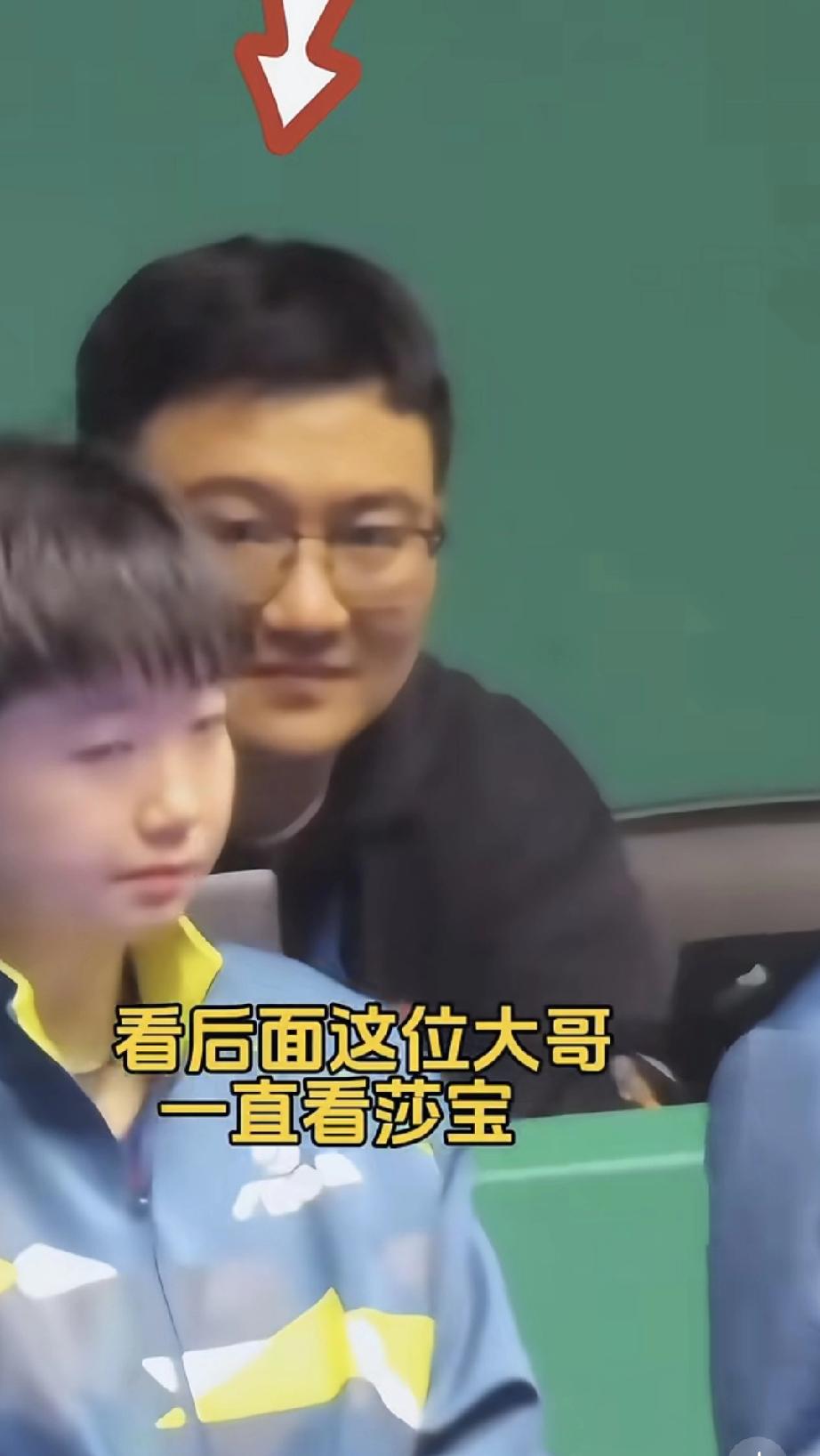 莎莎在前面聊天，后面大哥露出宠溺的笑，还拿出手机拍。莎莎不比赛的空档就是坐着和