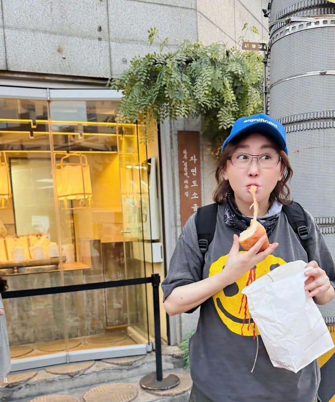 蓝心湄大街上吃面包，T恤上红色印记好像是从面包上流下的番茄酱。