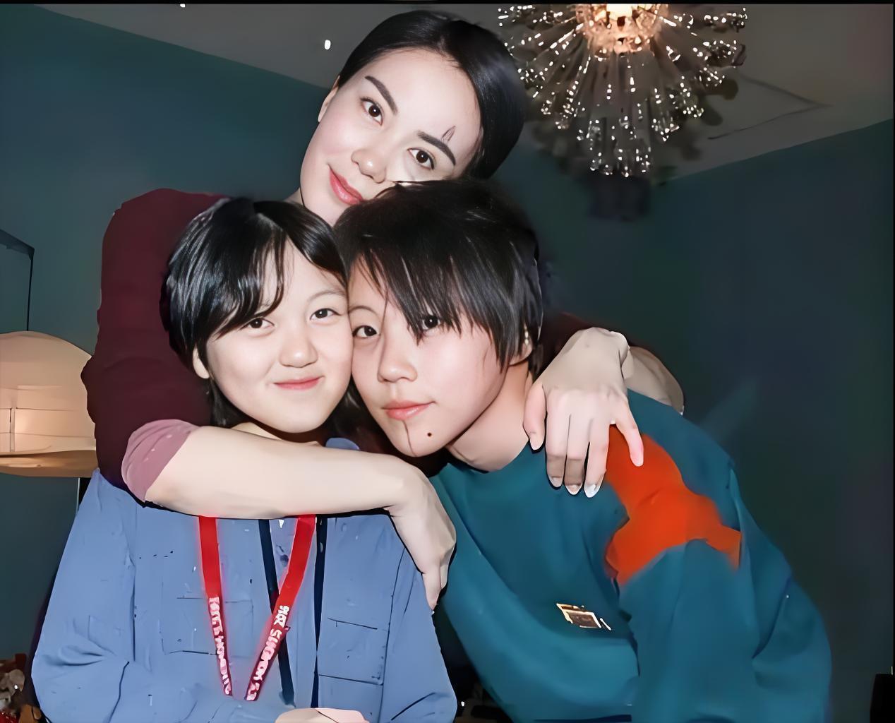 王菲和她的两个女儿。王菲在后面搂着两个女儿，母女三人头靠着头，很是温馨。她的两个