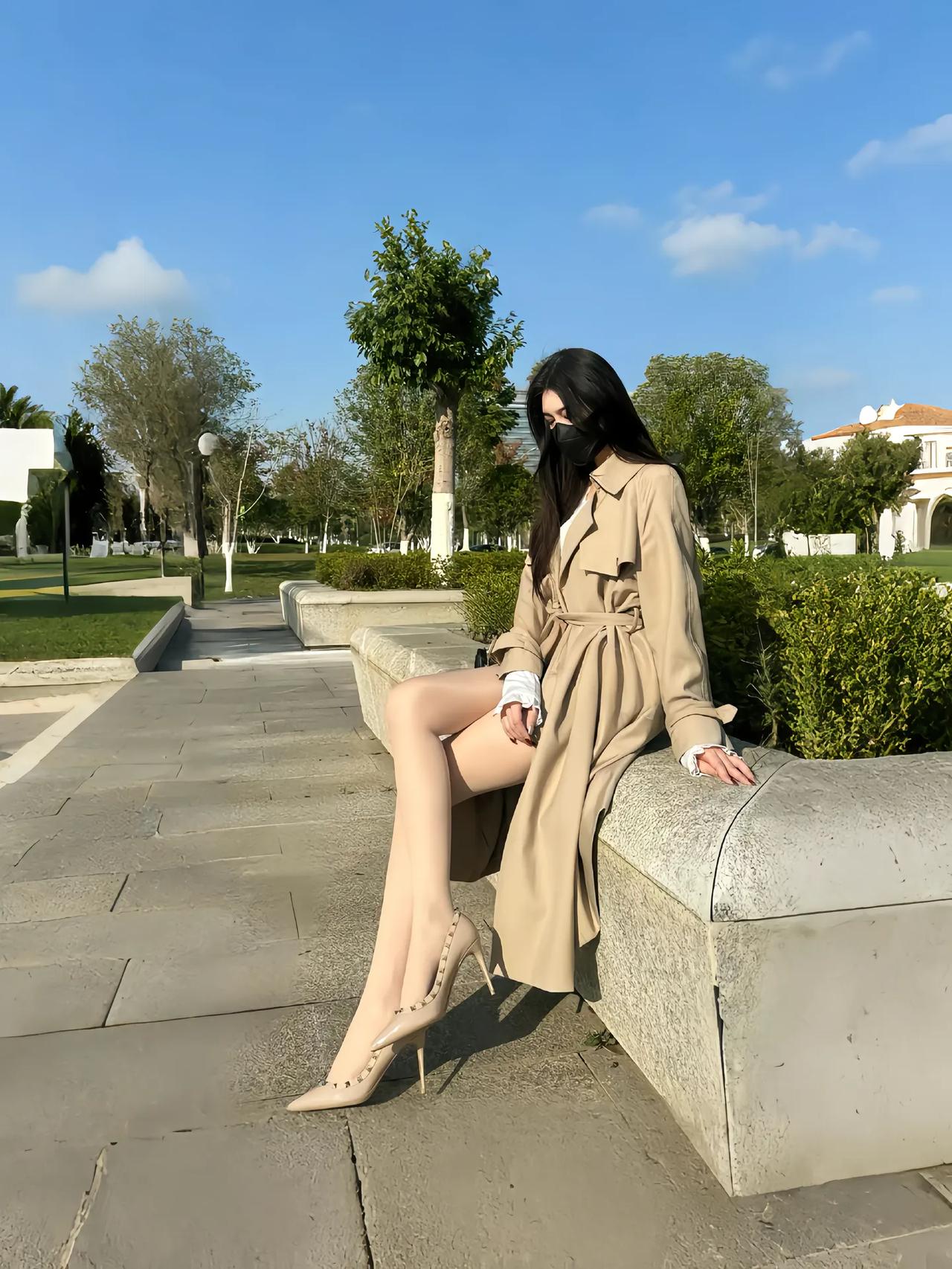 卡其风衣裹着晴日的软，鞋尖那抹红是风里藏不住的小雀跃。长椅浸在暖光里，椰影轻摇，