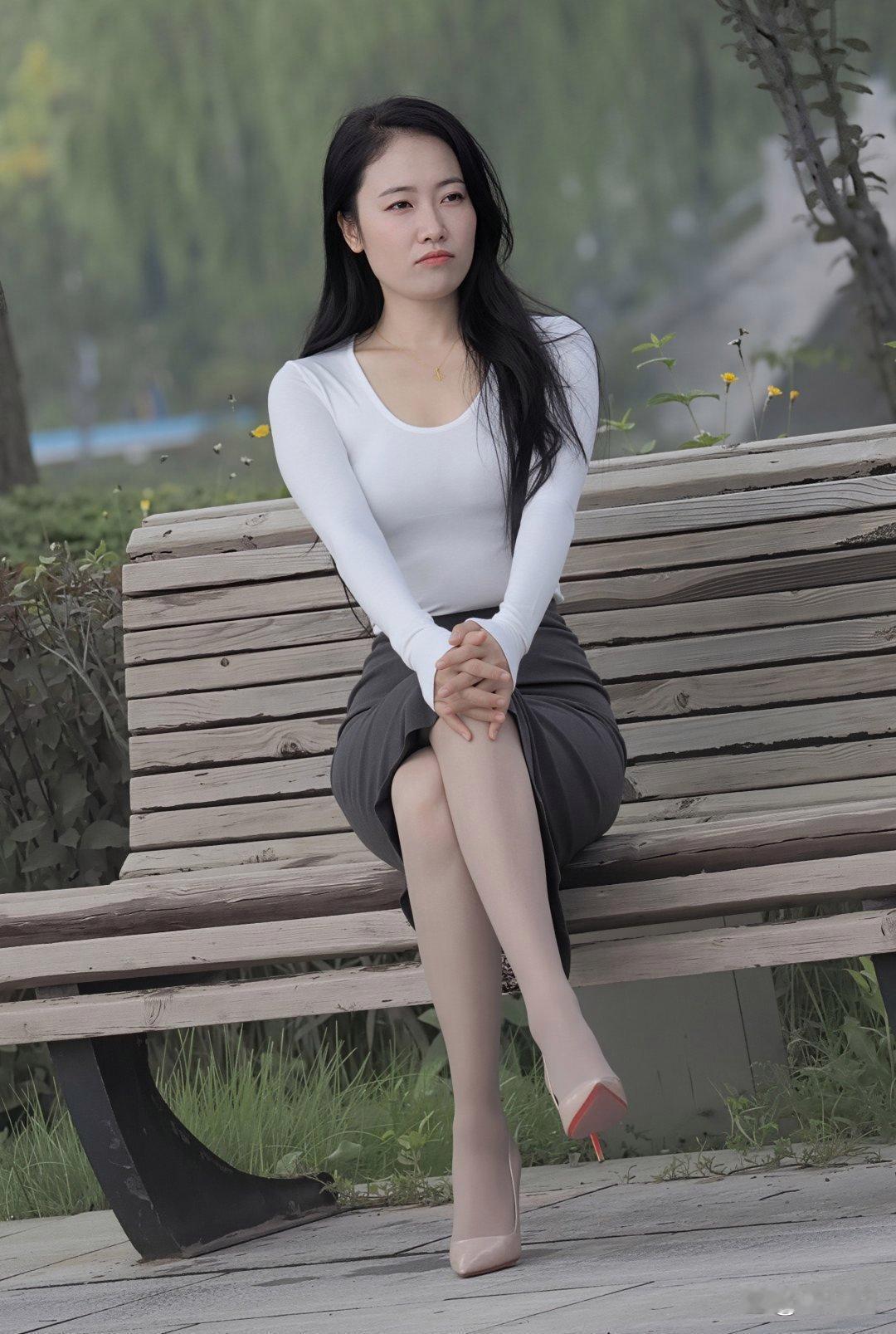 随手拍记录美好的点滴公园长椅上，白色长袖贴着肩，深灰半裙垂下来，浅粉高跟鞋踩在草
