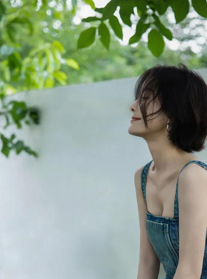 秦岚穿牛仔吊带裙，直角肩、锁骨杀太绝，皮肤嫩得能掐出水，抬手碰叶的瞬间，性感直接