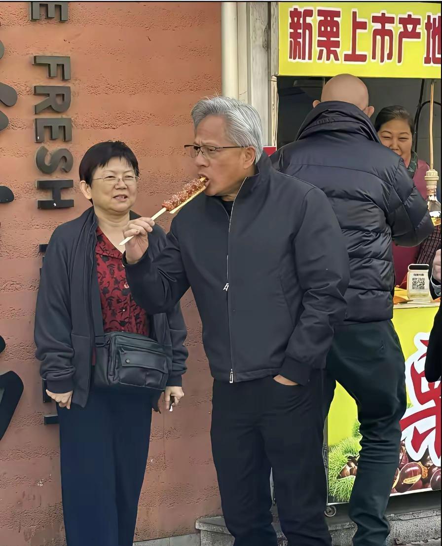 英伟达总裁黄仁勋在北京街头吃冰糖葫芦，这次他没有穿皮衣，一脸深色夹克外套，头发花