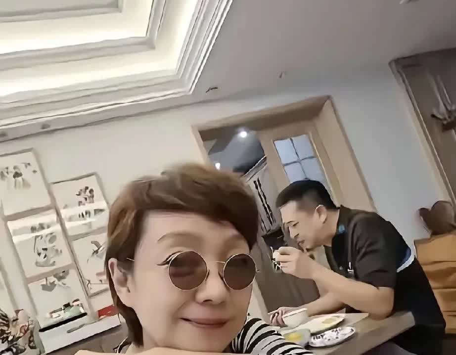 张嘉译在吃早餐王海燕戴了个小墨镜笑不滋的拍照，王海燕穿着一件很平常的条纹