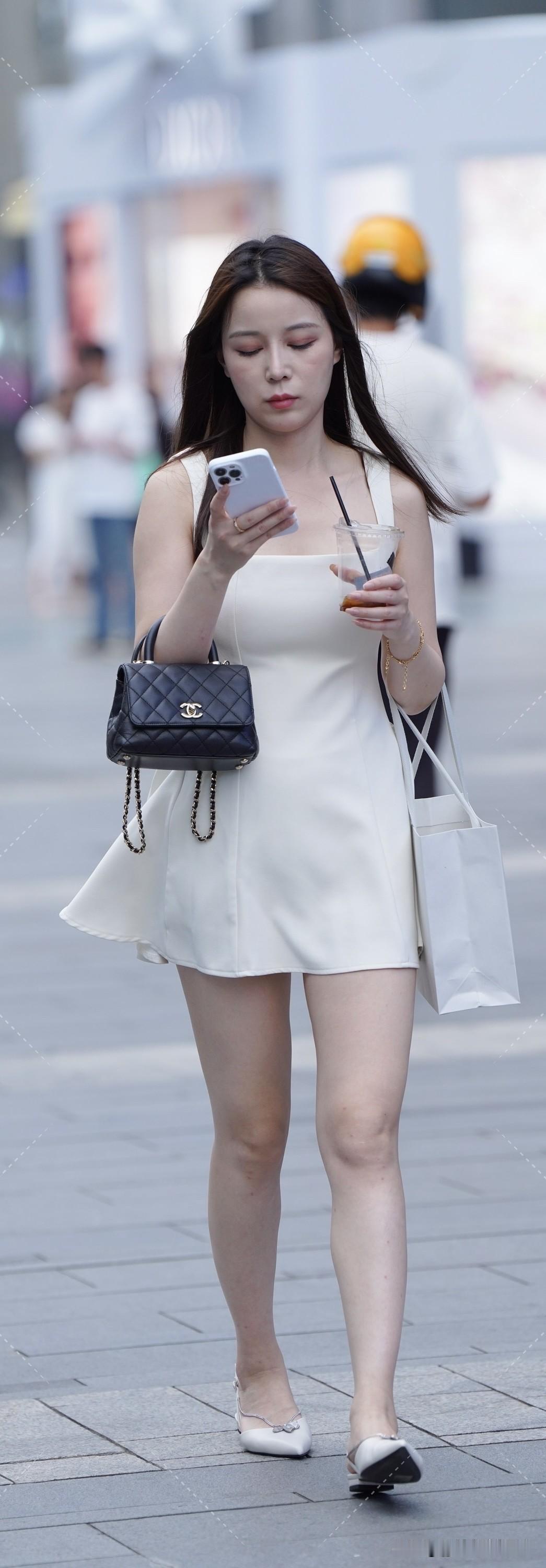 优雅白裙穿搭，手机与咖啡相伴，漫步街头，尽显时尚魅力。