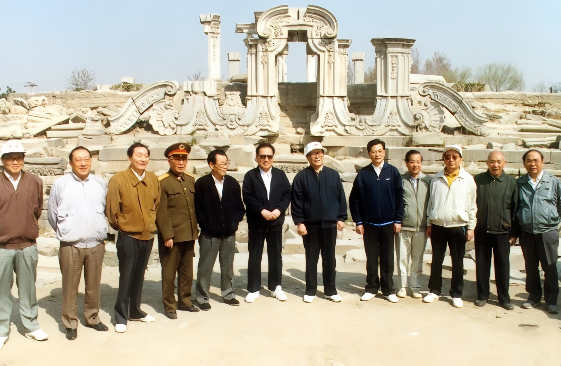 请看这张合影，后面的背景是圆明园内的西洋楼遗址。江同志和胡同志站在中间，都穿着便
