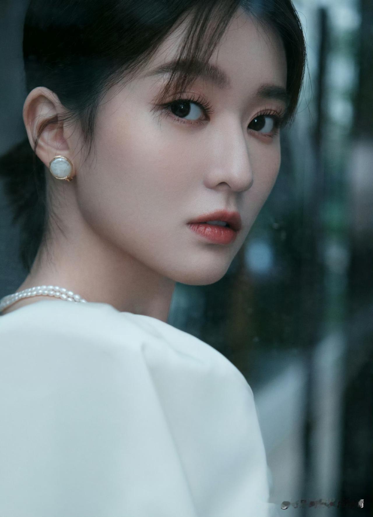 乔欣一袭白裙出镜，缎面材质勾勒曼妙身姿，泡泡袖设计添复古又柔美。照片中乔欣珍