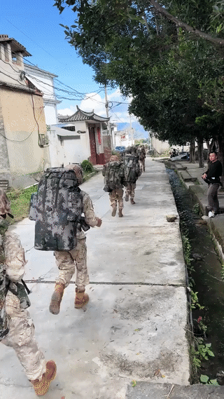网友在一个古镇里意外偶遇一群正在参加野外训练的解放军战士。当时他们正在成群结队