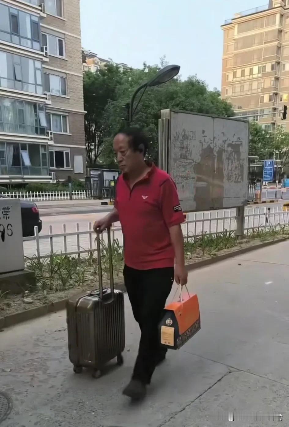 这是相声演员牛群最近从山西参加活动回北京住宅的情景。他穿着朴素，一脸沉重，右手推