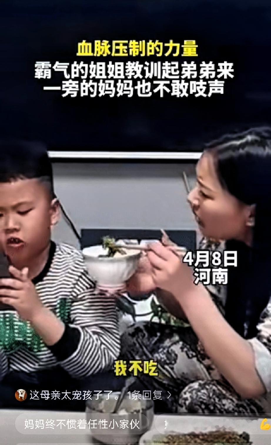 近日，河南，弟弟吃饭时只顾玩手机不愿意吃饭，妈妈端着碗把饭喂到嘴边:“来，儿子吃