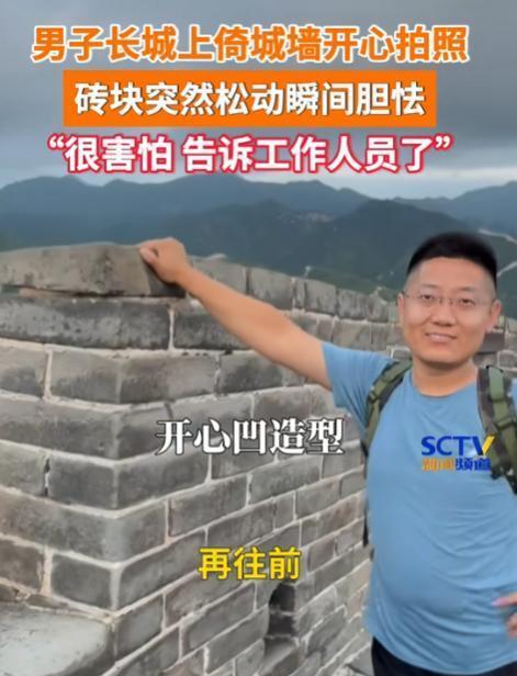 北京，一男子到游玩长城时，倚靠在墙砖上面拍照，不料，手碰到的那块砖头突然松动，男