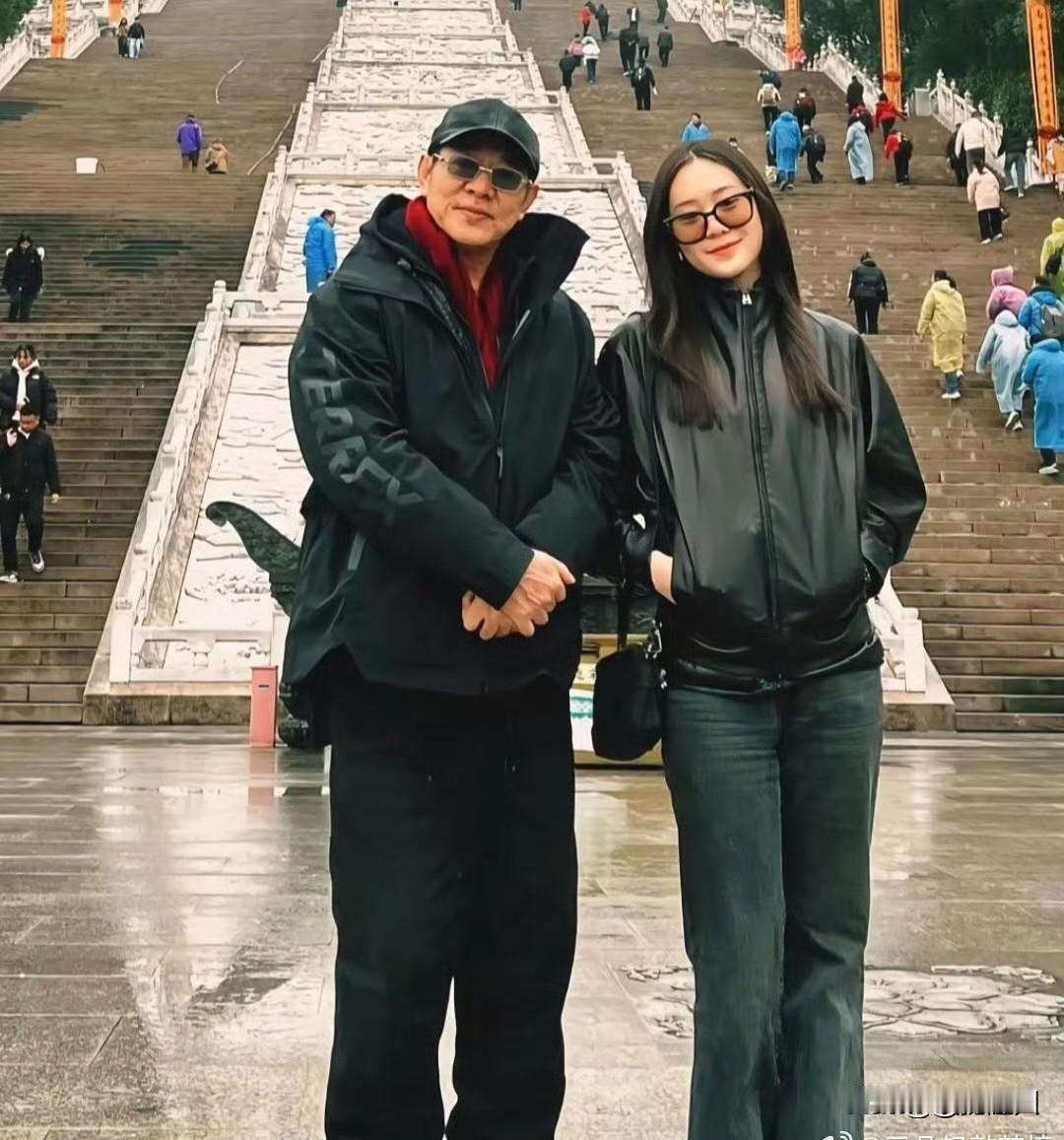 李连杰带22岁小女儿去安徽九华山祈福。照片中，李连杰身着黑衣、戴墨镜，打扮朴