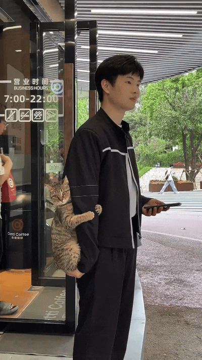 注意看！今天又在咖啡店门口碰到这小哥了，他一只手揣兜，另一只手托着怀里的小狸花猫