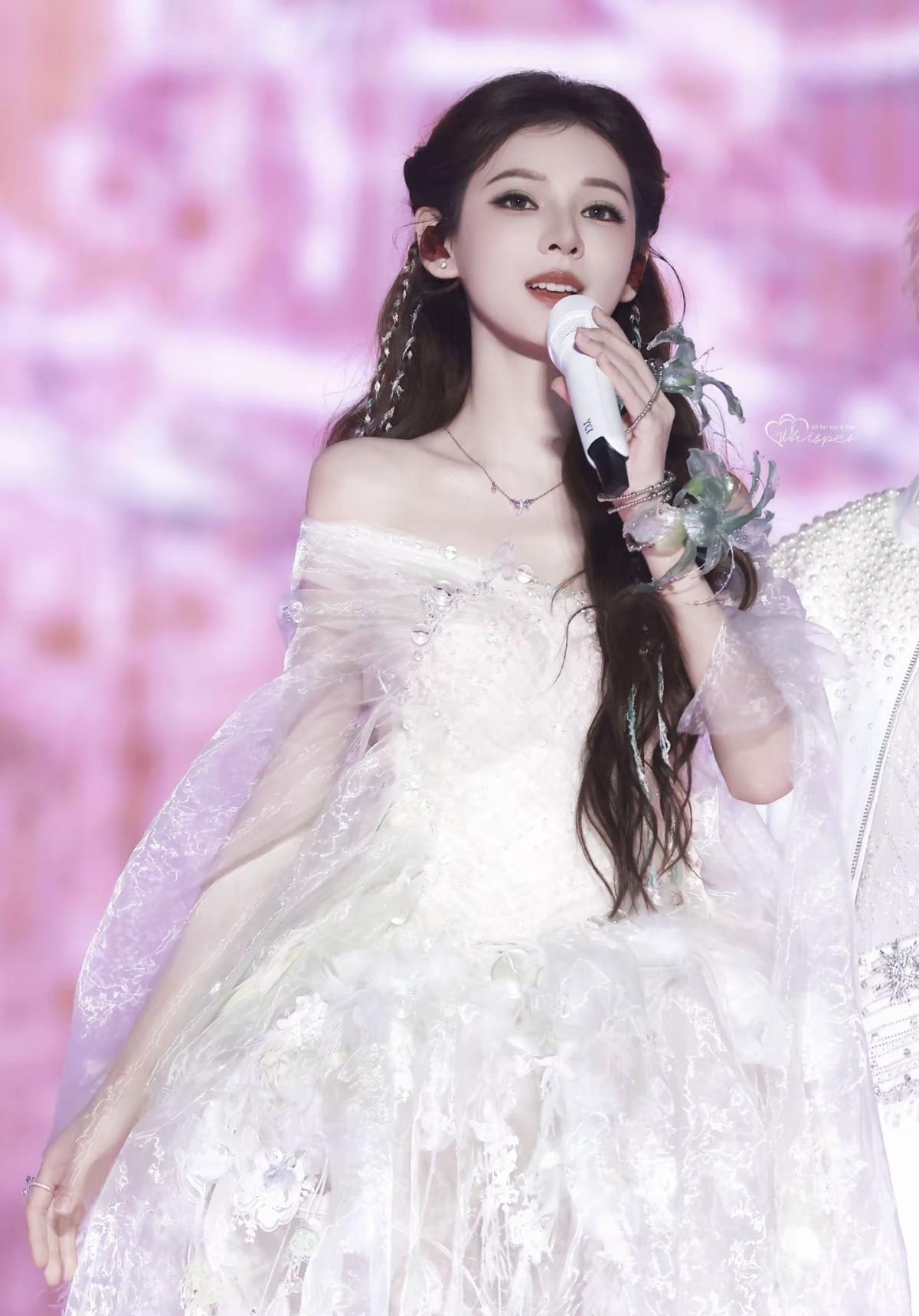 粉紫灯光下的张予曦，是自带柔光滤镜的舞台精灵[比心]露肩白纱裙勾勒出优雅肩线，手