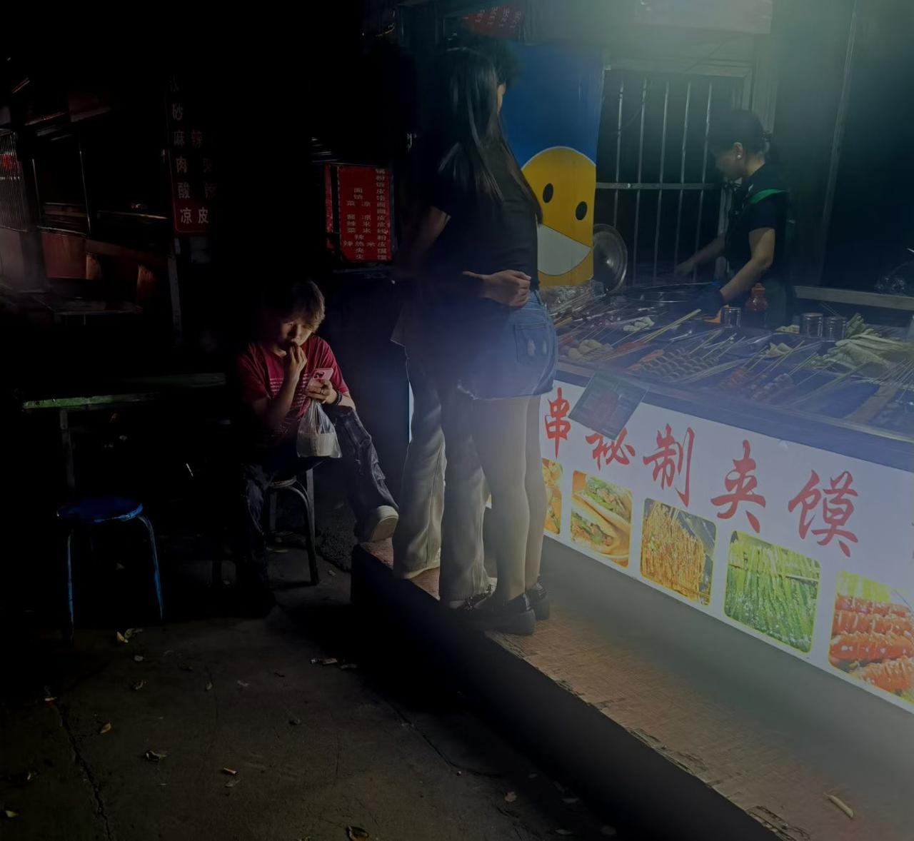 炸串摊前，拥抱在一起的小情侣。姑娘：你能吃辣不。小伙：不能吃辣还不能活着吗。这真