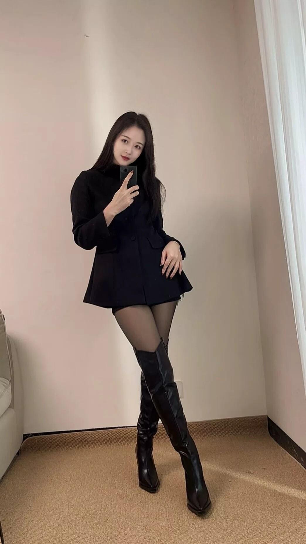 黑西装裙叠着黑丝与长靴的飒爽，把冷艳的气场揉进自拍的瞬间，简约的黑调里，藏着不被