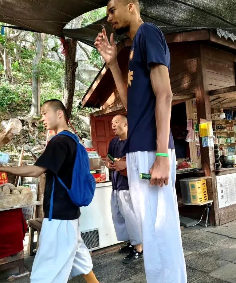 文班亚马跟着少林寺的师兄们一起去小卖部买东西，这根黄瓜，在文班亚马的手中，显得娇