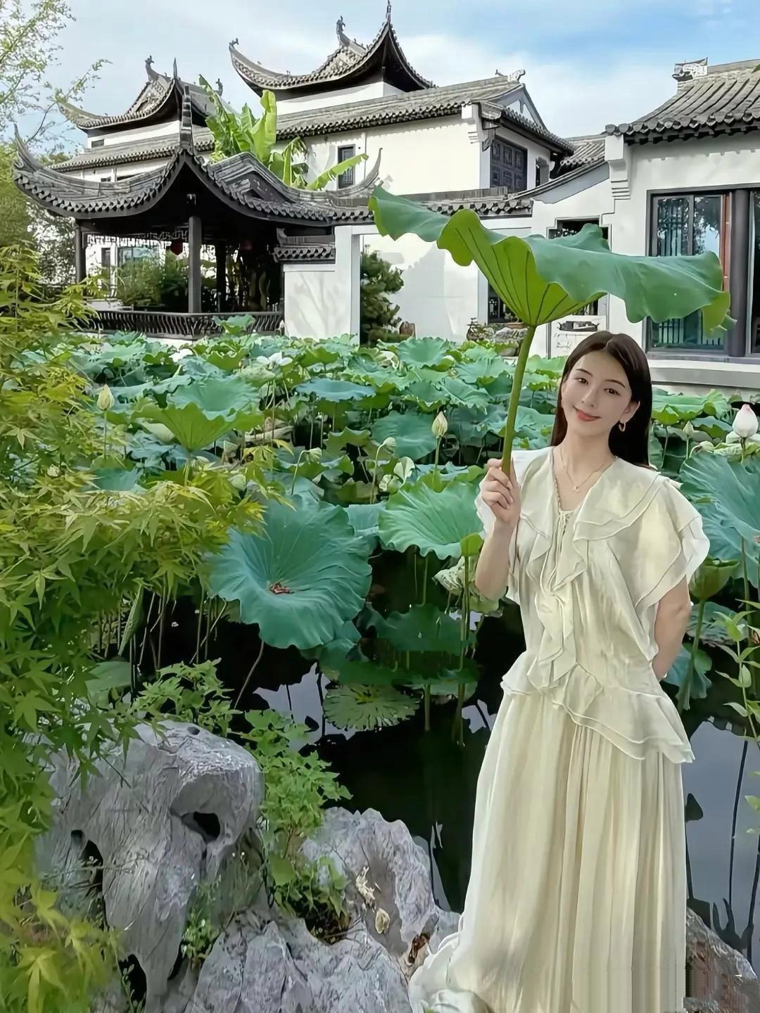 郭富城娇妻方媛带近日回安徽老家度假，她在古村落前的荷花池拍摄写真，手举碧绿的荷叶