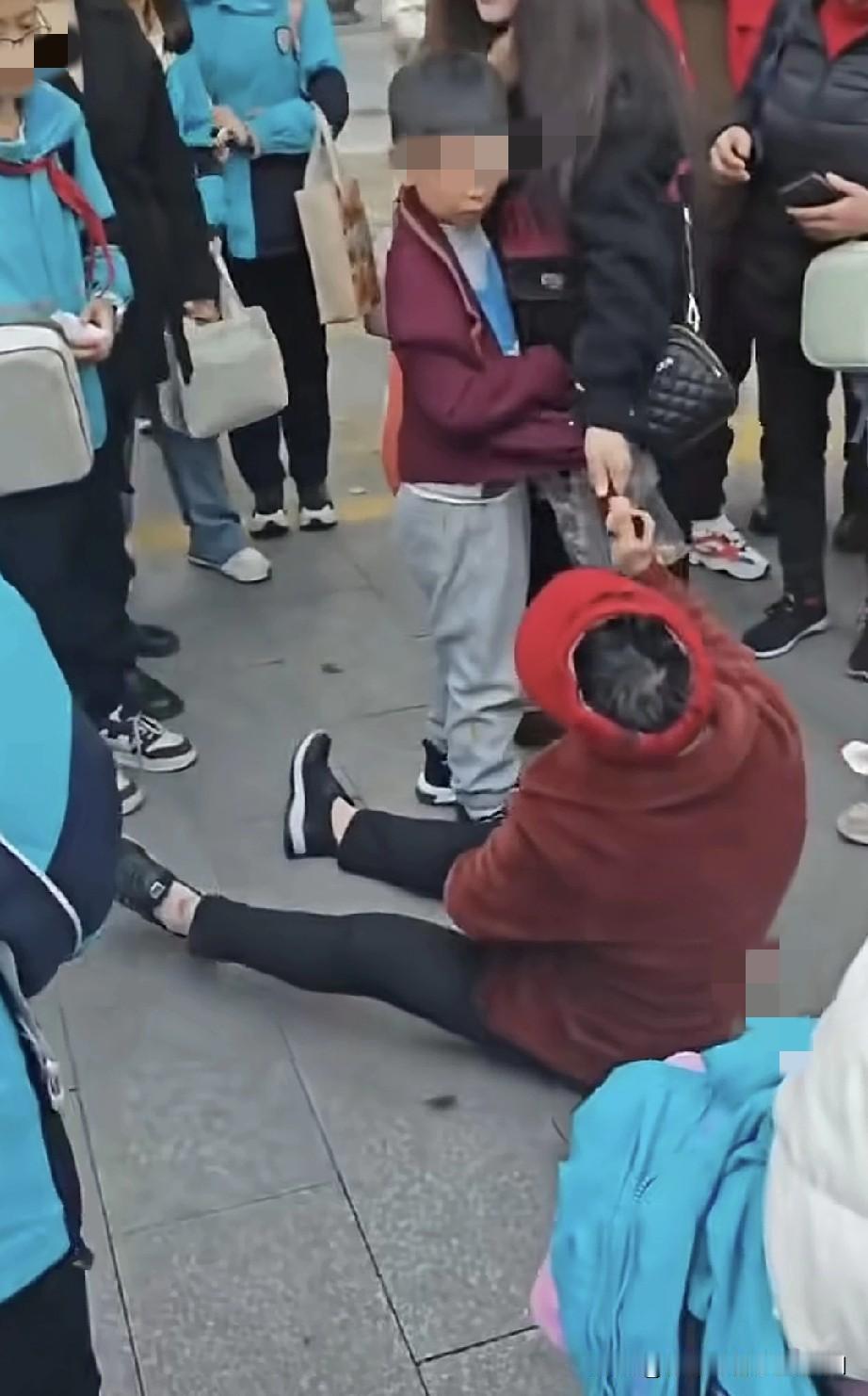 学校门口一位老奶奶坐在地上，双手紧紧揪住一名小学生的衣服，死活不让他走，坚称是被