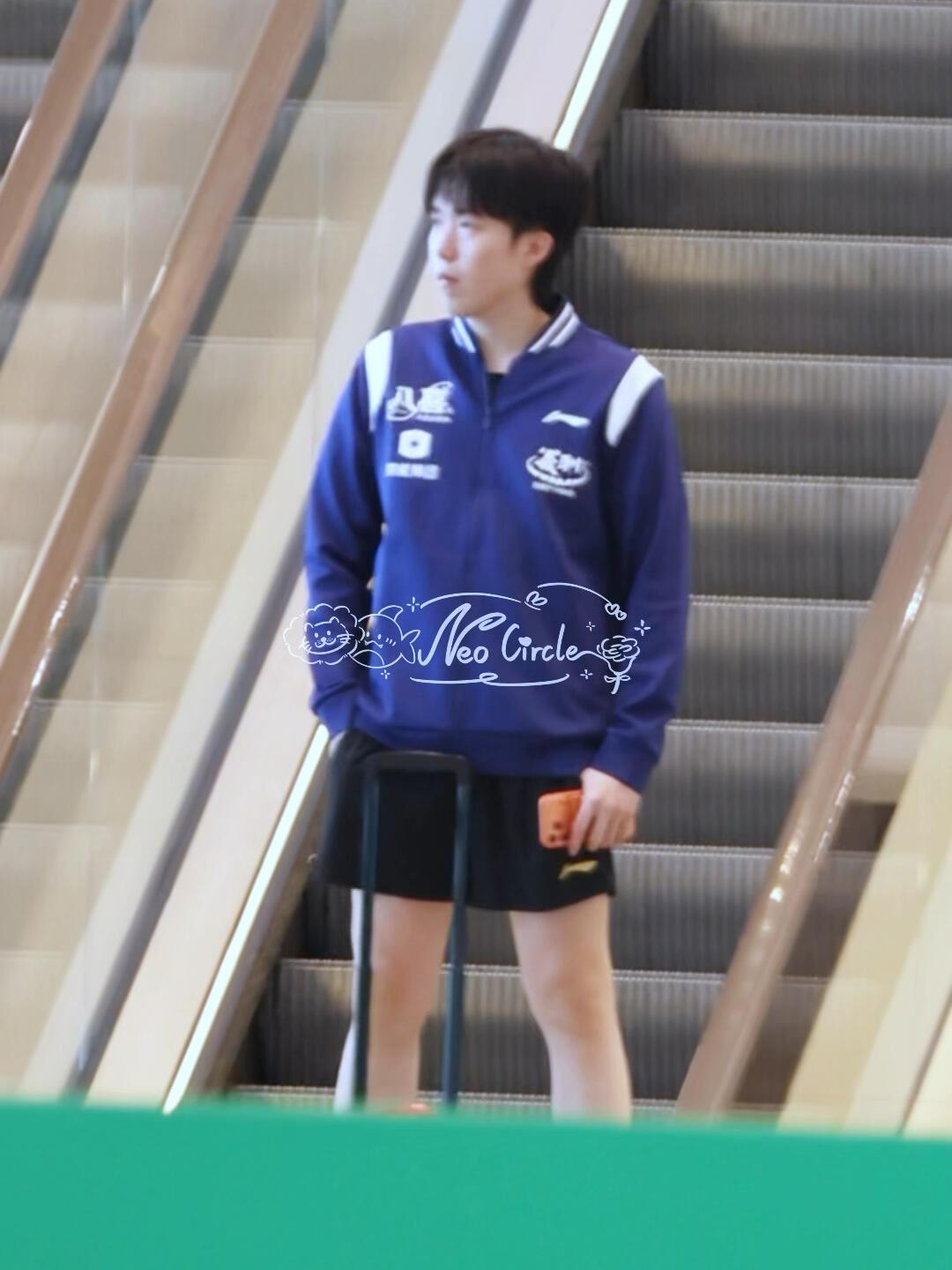 小王上训，单手插兜，一个手里拿着最新款橙色手机，裤兜是没地方放了！头哥真白净简