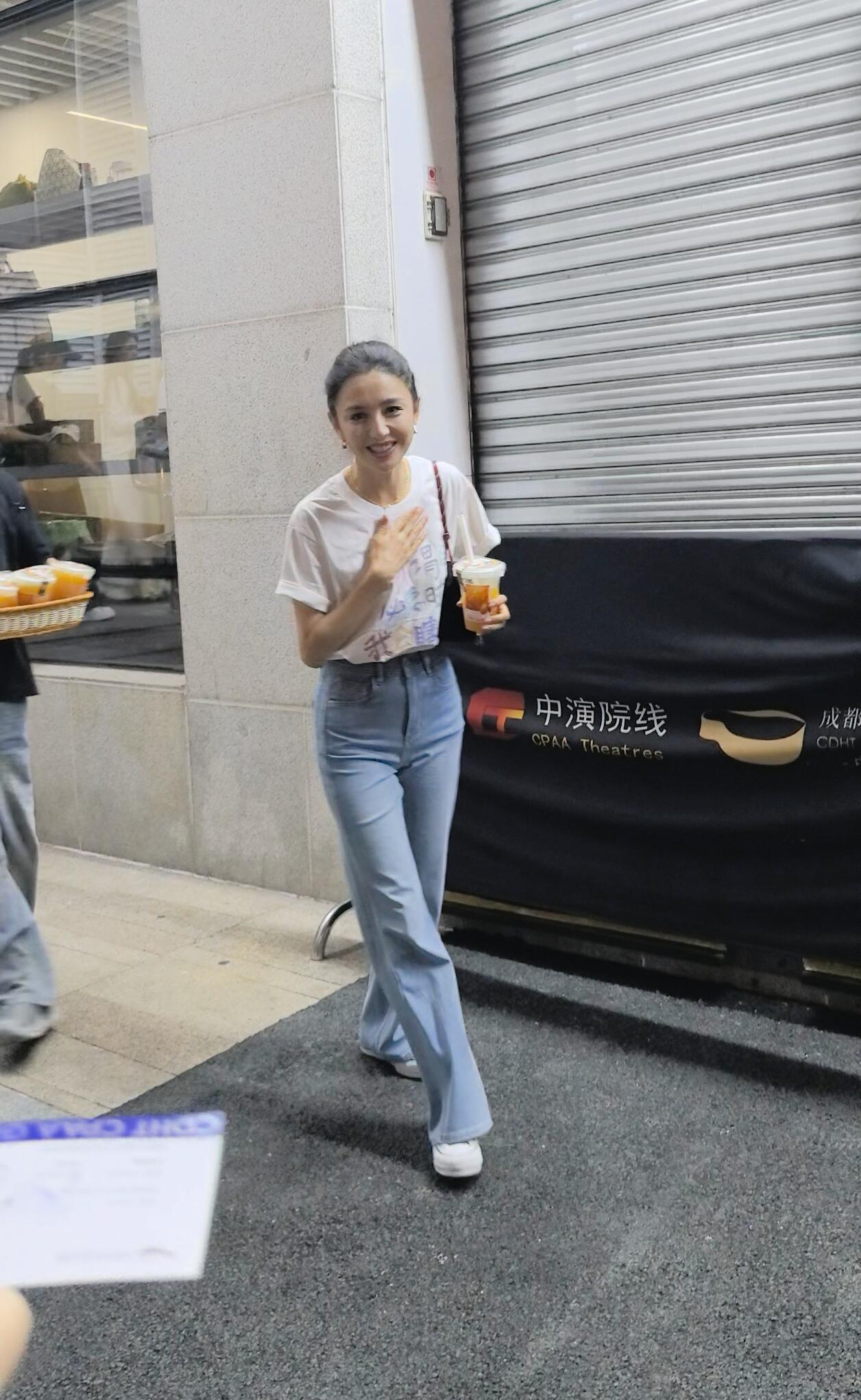 路人镜头中的佟丽娅，简约白T恤配牛仔裤，简简单单也很好看！高丸子头清爽减龄，弱