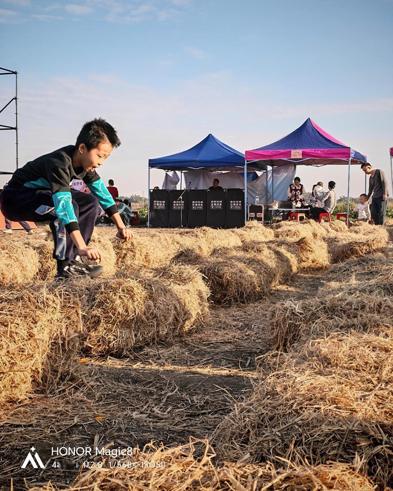 荣耀Magic8抓拍了几张小孩在草垛上跳跃的照片，发现成片质量真的很高。先说明一