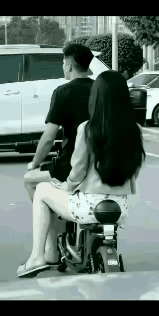 美女坐在电动车上，频繁回头，不知道在看什么？