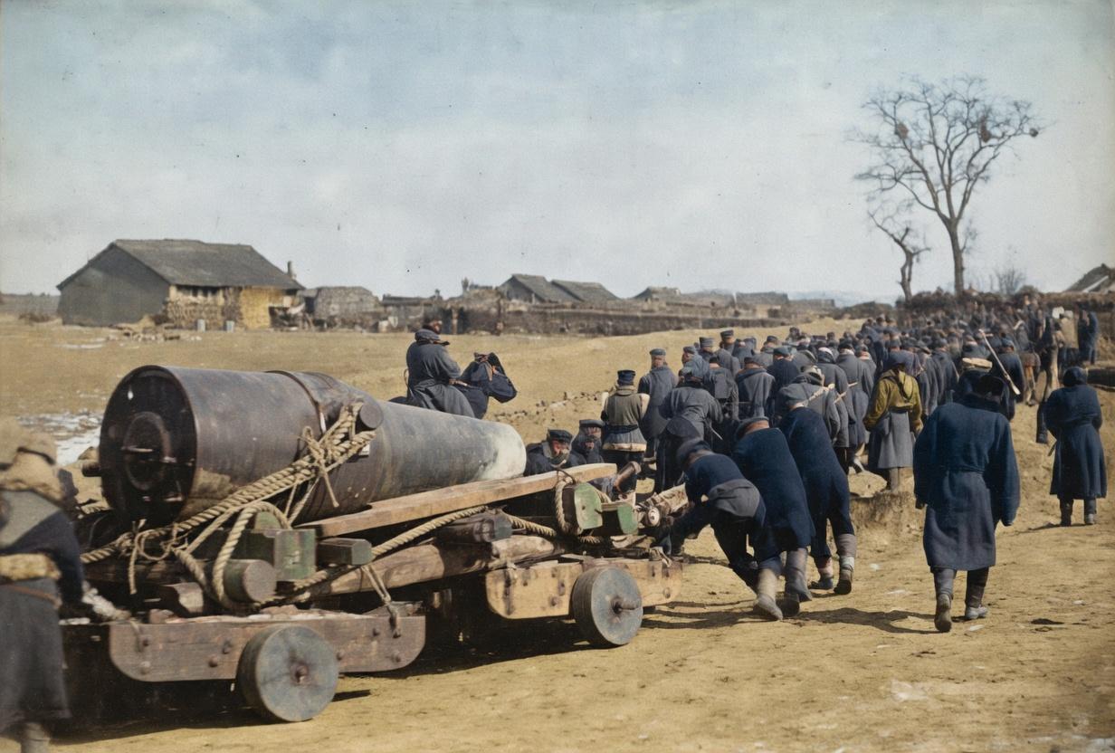 1904年，日俄战争旅顺前线。上百名日军士兵正用最原始的木轮车，拖拽着一门28