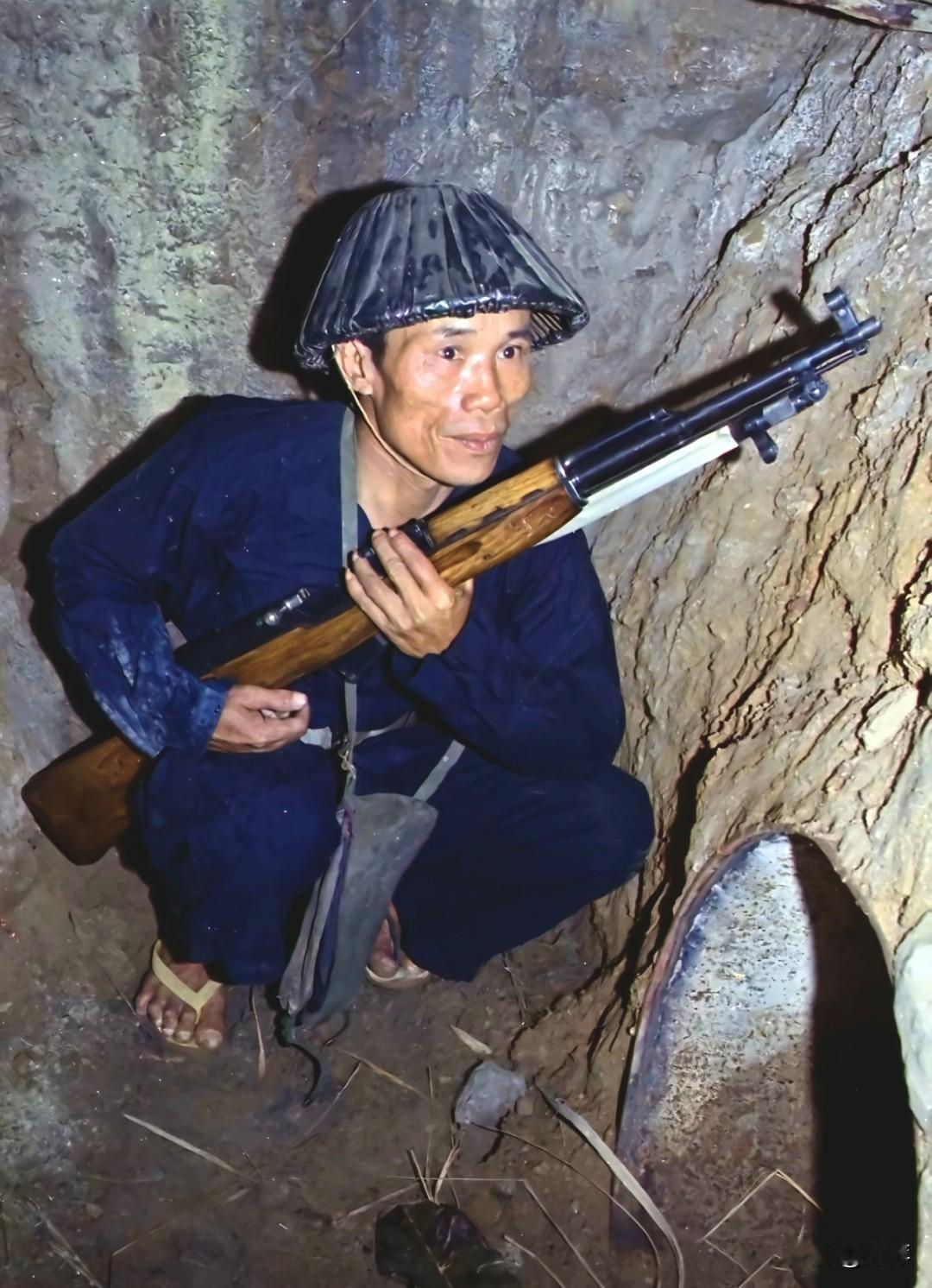 这是越南战争时期，一名越共游击队员在地道内的画面。他身着黑衣、头戴斗笠，手持SK