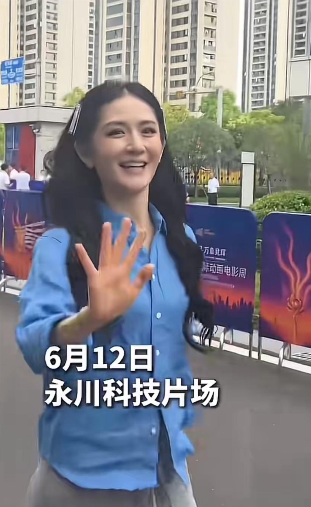 谢娜现身重庆永川科技片场，她穿着蓝色长袖衬衣，大波浪长卷发，化着淡妆，面带微笑走