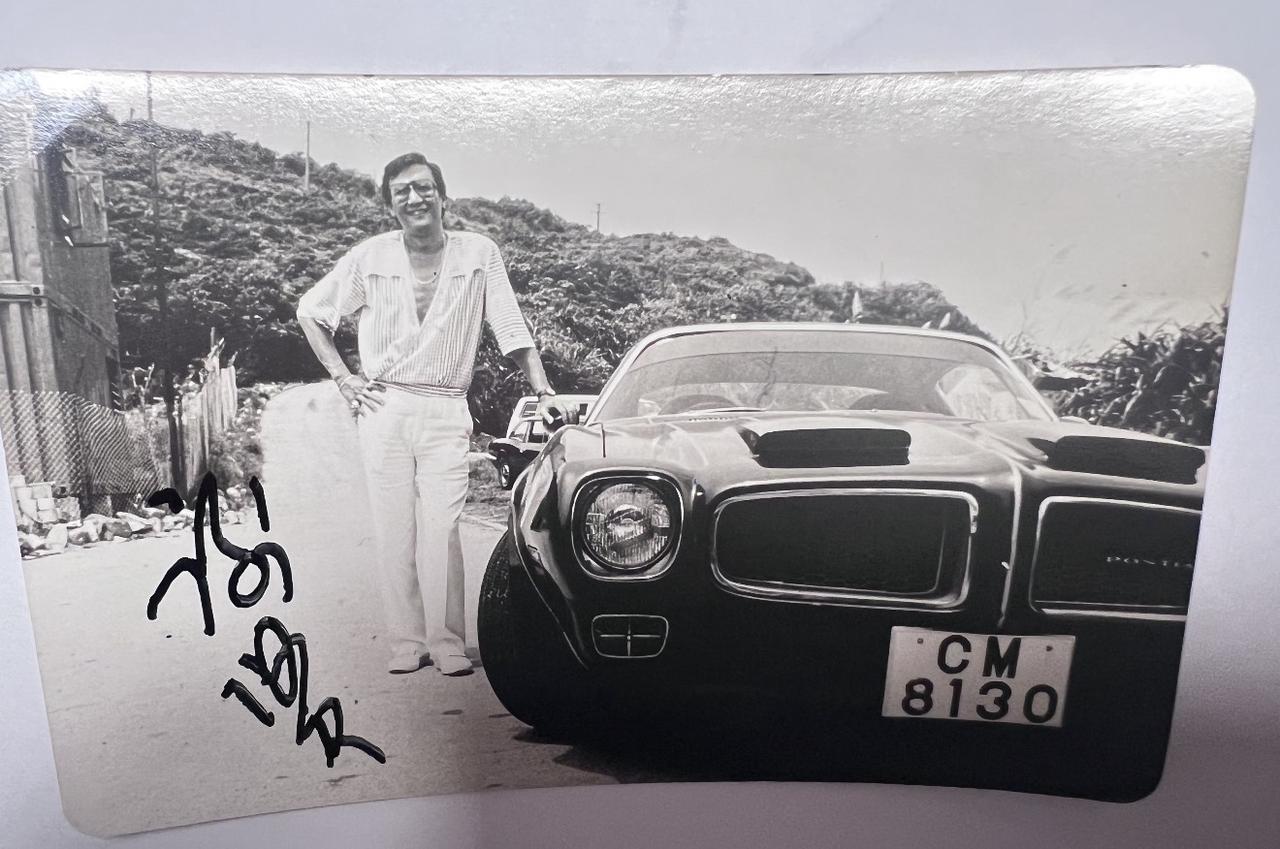 一张谢贤年轻时的照片，“四哥”站在一辆黑色轿车旁边，脸上露出开心的笑容。那时