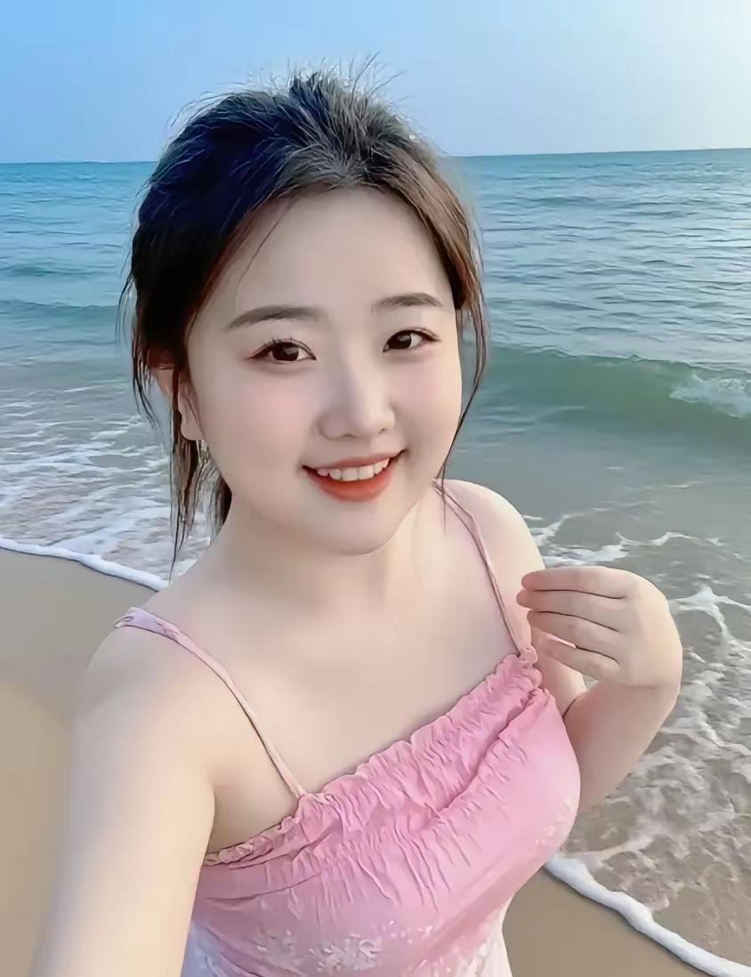 浪花中的情诗她立于海边，粉裙似盛放的花，与海天共绘浪漫。海风轻拂发丝，裹挟着咸