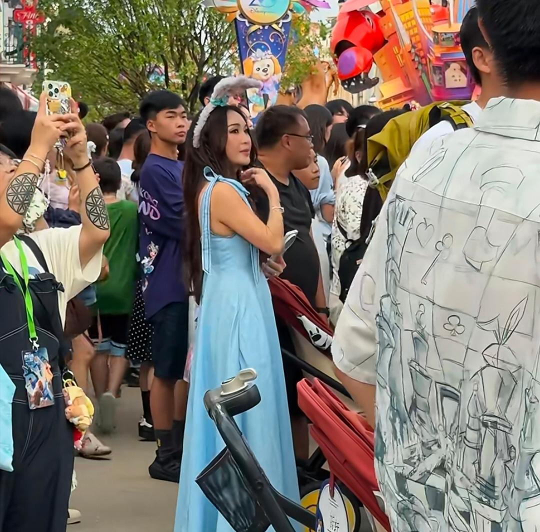 温碧霞在香港迪士尼乐园游玩，她穿了一条蓝色裙子，打扮像少女，状态看起来真好！