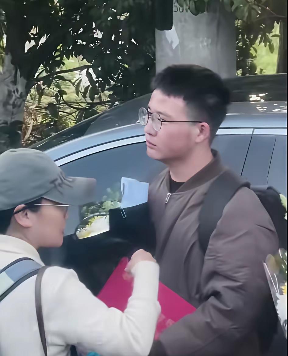 送别张雪峰老师队伍里这抹耀眼的红，成了泪人的一幕！这个戴着眼镜的男生，手里拿着