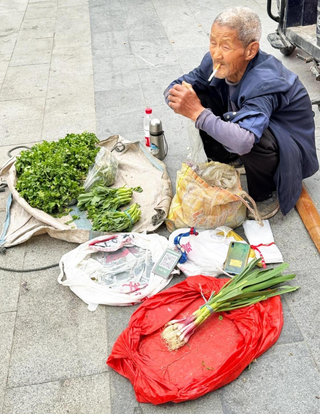 我问摆摊卖菜的大爷：生意看着冷清，何苦天天守在这儿遭罪？大爷抬眼瞥了我一下，语