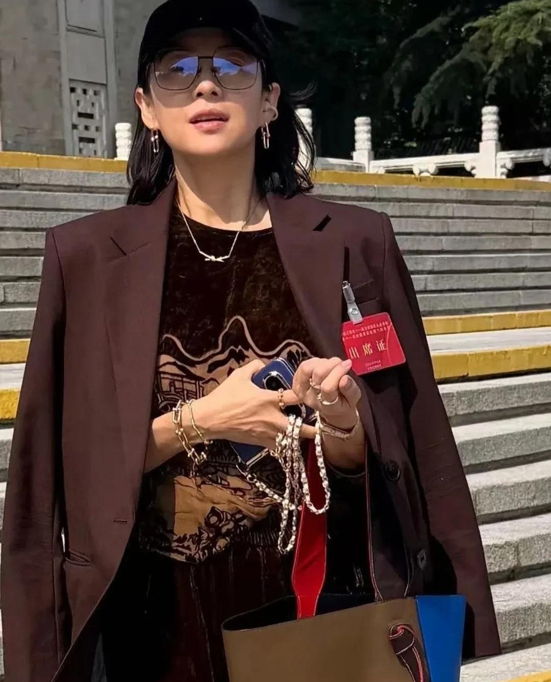 章子怡现身北京友谊宾馆，一顶黑棒球帽配咖啡色西装，硬是把“随便穿穿”穿成了高配版。她耳朵、脖子、手腕